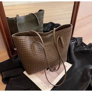 Detail of a brown woven PU leather tote bag with a forest green mirror reflection