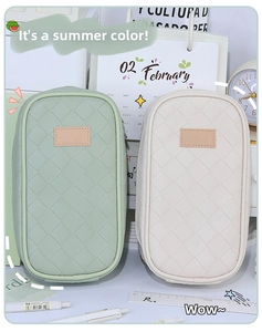 Detail of woven texture stationery pouch in mint green and cream with leather logo tag