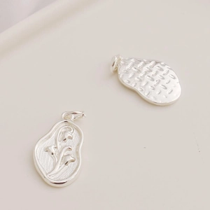 Detail of 925 sterling silver charms featuring floral relief and oval textured surfaces