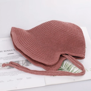 Detail view of the pink knit crochet sun hat with a strap on a fashion magazine