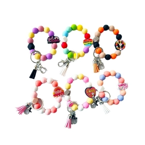 Variety of colorful silicone beaded keychain wristlets with tassels and charms on white base