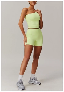 Vue complète de l'ensemble de sport vert citron avec brassière asymétrique et short galbant
