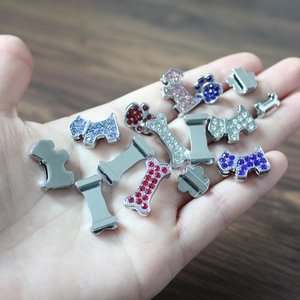 Detailed view of colorful rhinestone paw and bone charms held in palm for size reference