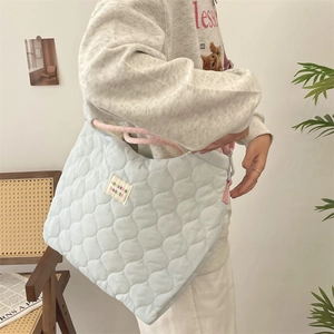 Détail du sac fourre-tout matelassé bleu clair avec texture ondulée et anses roses