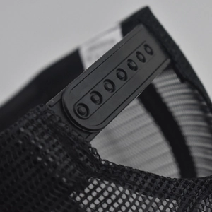 Close-up of adjustable snapback closure and breathable mesh fabric on black trucker hat