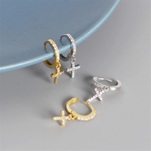 Detailed macro view of gold and silver cross hoop earrings with pavé set zircon stones