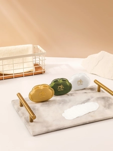 Cloud-shaped portable soap boxes in green, yellow and white on a marble tray