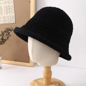 Minimalist black plush bucket hat with thick textured fabric on a wooden display stand