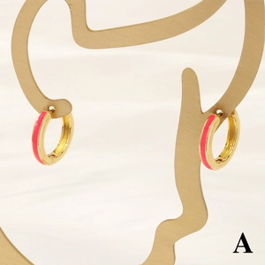 Detail of 18K gold hoop earrings with pink enamel finish on minimalist jewelry display