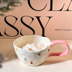 Close-up of ceramic mug with pink handle, fruit patterns and fluffy marshmallows