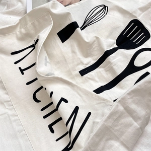 Detail of white cotton linen apron with black kitchen utensil print and text