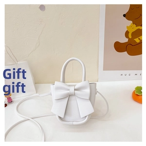 Detailed view of a white bow crossbody bag with a handle in a cozy lifestyle setting
