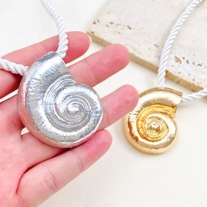 Detail view of gold and silver shell pendants on white twisted cords for beach jewelry set