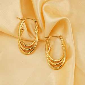 Triple layered gold oval hoop earrings in 18K titanium steel on champagne silk backdrop