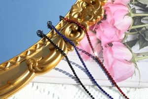 Detailed shot of sparkling rhinestone necklaces in black, blue, and red on a vintage frame