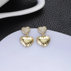 Macro detail of vintage gold heart earrings with zircon inlay and textured metal finish