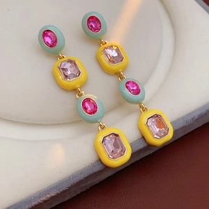 Macro shot of vintage style earrings with mint green frames and pink gems on white felt