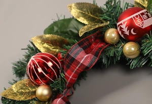 Detailed close-up of Christmas wreath with pine needles, gold leaves and plaid ribbon
