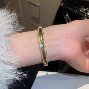 Macro shot of 18k gold-plated bangle featuring a sparkling orb logo with pavé cubic zirconia