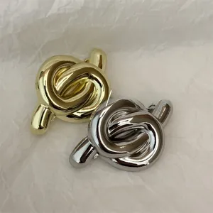 Close-up of knot-shaped metal hair clips in shiny gold and silver finishes