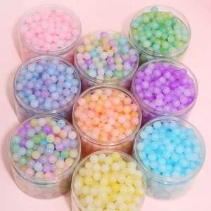 Nine jars of colorful acrylic jelly beads for DIY jewelry making on a pink background