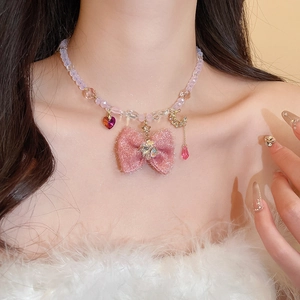 Detail of pink bow pendant with heart, star, and moon charms on beaded necklace