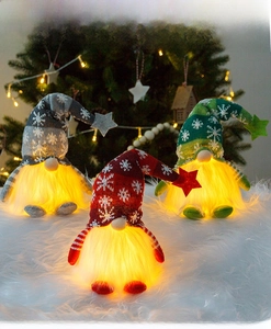 Close-up of three glowing Christmas gnomes with warm LED lights and snowflake knit hats