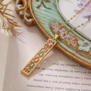 Close-up of golden necklace featuring a rectangular DREAM pendant with colorful zircons