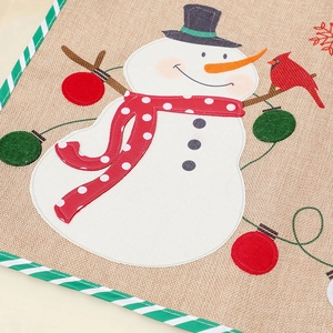 Detailed close-up of burlap Christmas placemat featuring snowman and red bird embroidery