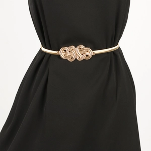 Detail of gold metal elastic waist chain featuring a decorative woven knot buckle design