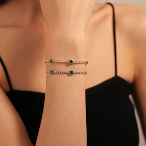 Close-up of green emerald zircon bracelets in gold and silver plating on woman wrist