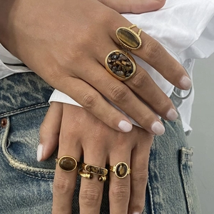 Gold stainless steel rings set with natural tiger eye stones worn by a model