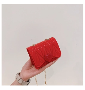 Close-up of small red heart-shaped silicone crossbody bag with gold chain and V-quilting