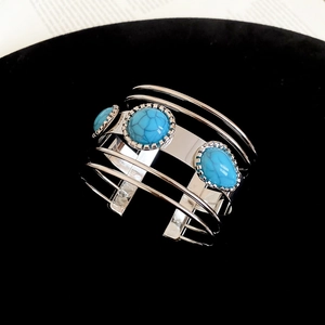 Detail of silver multi-layered cuff bracelet with turquoise stones on black velvet