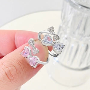 Detailed view of silver bow rings with pink and white heart-shaped zircon stones