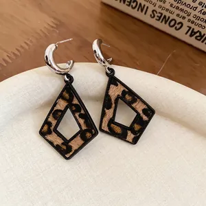 Boucles d'oreilles losanges à imprimé léopard avec tiges en argent sur plateau crème