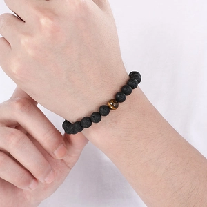 Detailed close-up of natural black lava rock beads and tiger eye stone stretch bracelet