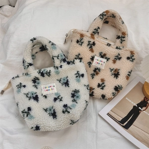 Detailansicht von zwei Plüsch-Lammwolltaschen mit Blumenmuster und Reißverschluss