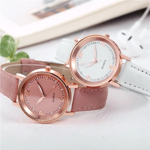 Luminous quartz watch with pink leather strap and rose gold case on a lifestyle desk
