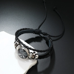 Détail d'un bracelet en cuir noir tressé avec perles en métal et breloque de tennis