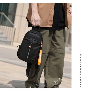 Close-up of black waterproof nylon chest bag with vibrant orange zipper details