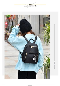 Detailed view of women's black oxford backpack with gold zippers and cute bear pendant