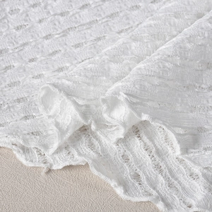 Détail du tissu en maille jacquard blanc montrant la texture riche et le motif plissé