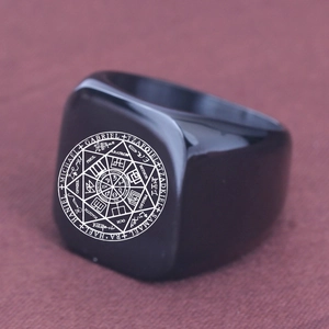 Macro shot of black stainless steel signet ring with engraved white celestial symbols