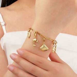 Golden titanium steel charm bracelet with shell, dolphin and bird pendants on model