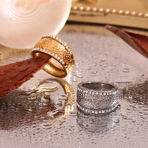 Macro detail of wide 18K gold and silver rings with pave diamonds and hammered texture