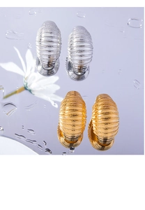 Detailed macro view of C-shaped metal earrings with spiral rope texture in gold and silver