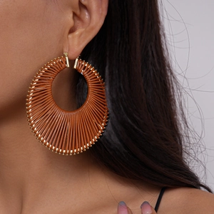 Close-up of model wearing boho brown woven geometric hoop earrings with gold metal edges