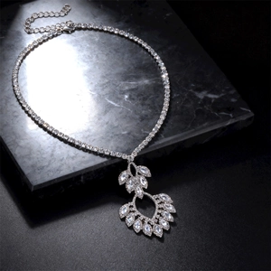 Detail of silver hollow teardrop pendant with sparkling zircon on dark marble stand