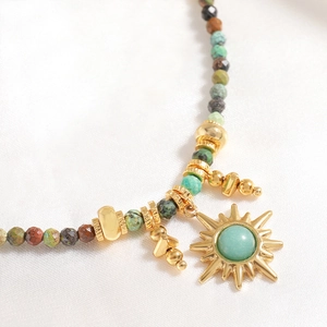 French vintage necklace with colorful natural stones and a golden sun pendant on white satin